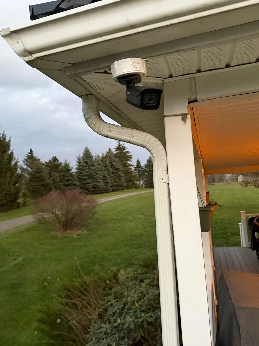 A dome camera under a house eave overlooking the back lawn.