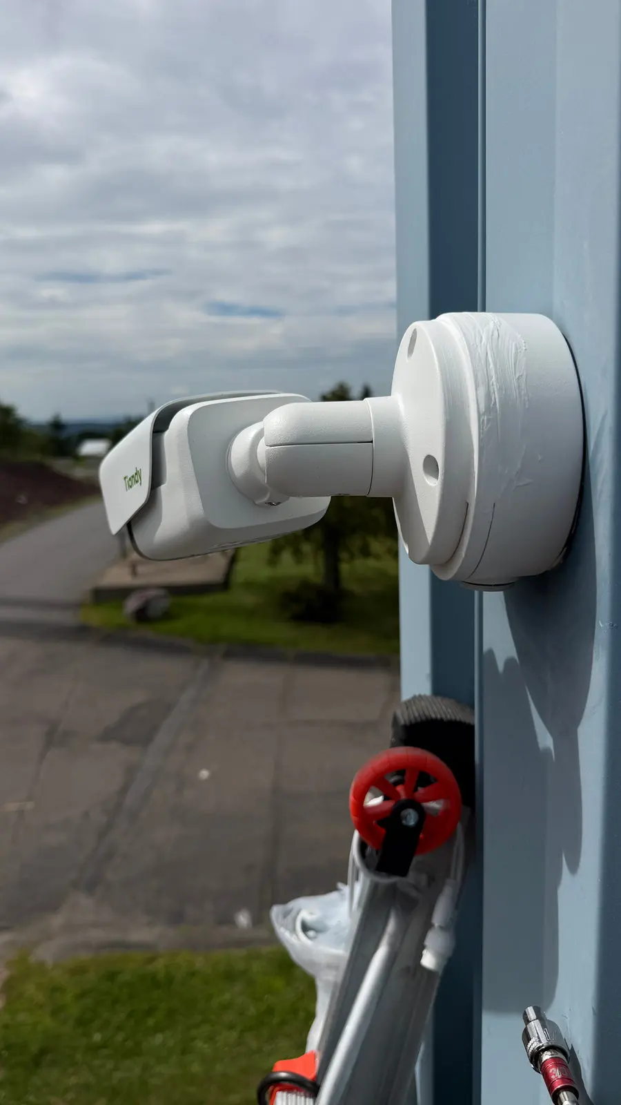 A bullet camera on a house corner aimed down the driveway.