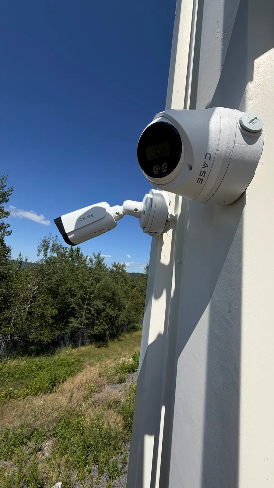 A bullet camera and a turret camera on the corner of a house.