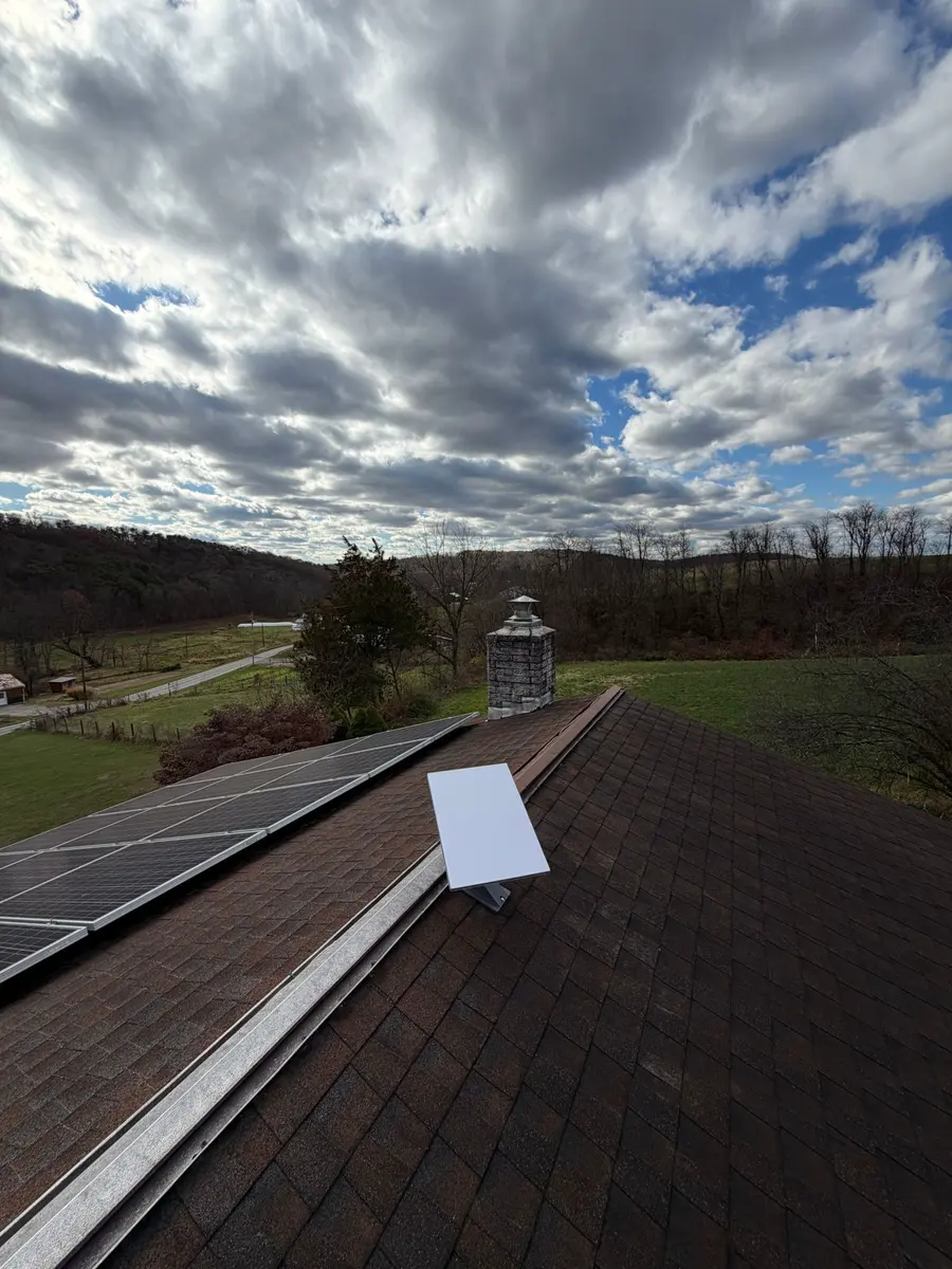 A Starlink dish on a roof next to solar panels.