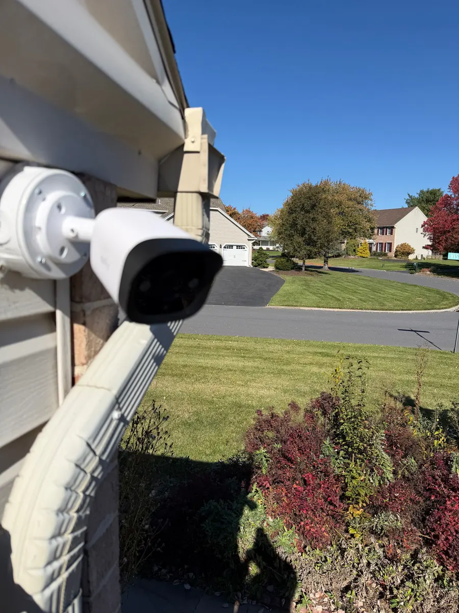 A white bullet camera on a house covering the front lawn and street.